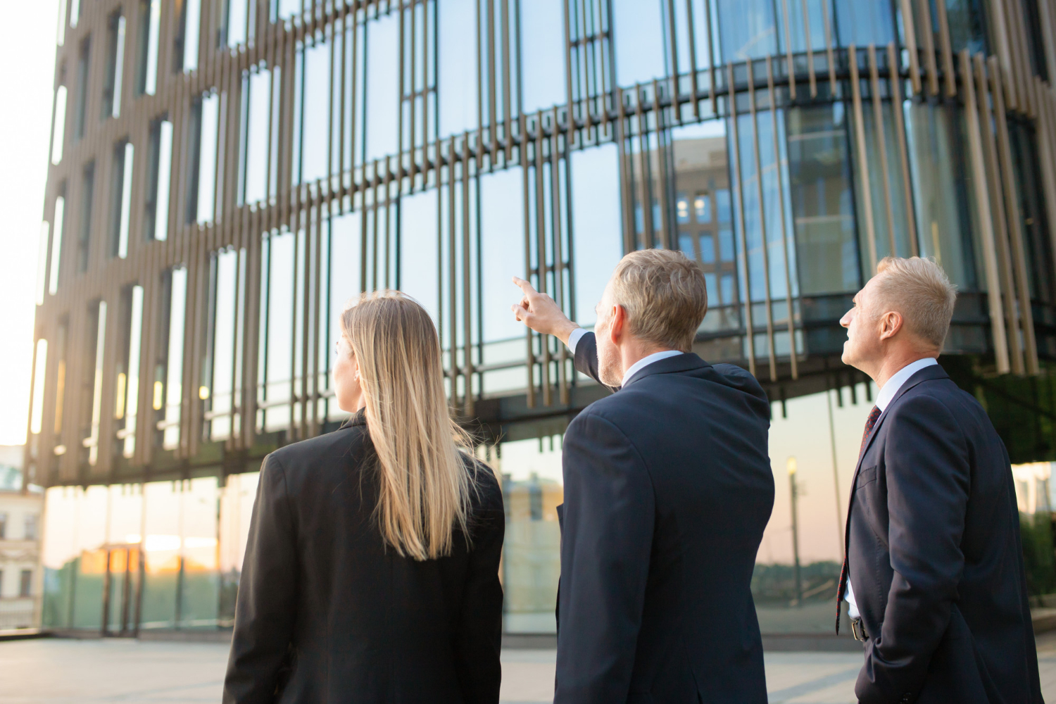 group-business-partners-formal-suits-pointing-office-building-meeting-outdoors-discussing-real-property-back-view-commercial-real-estate-concept